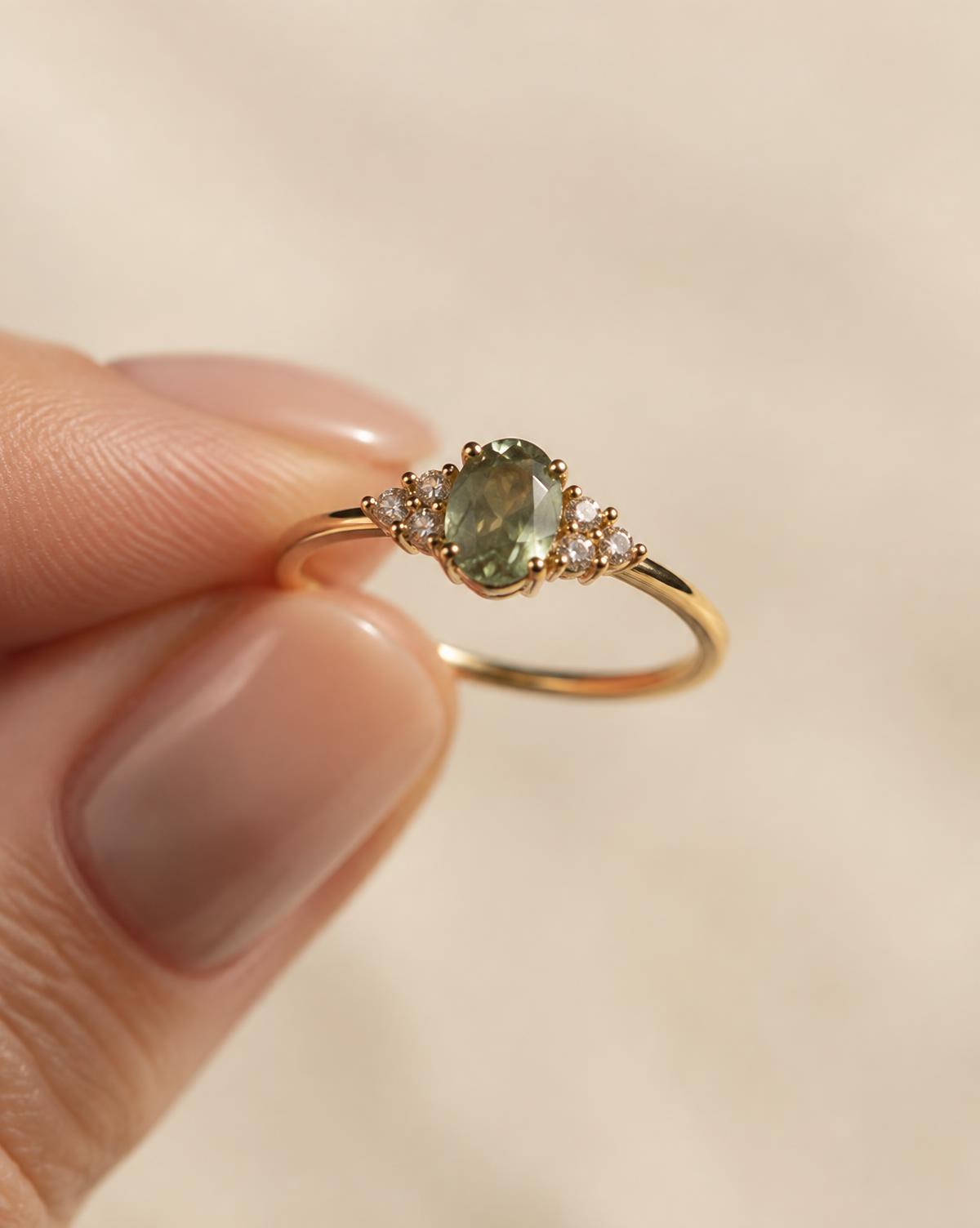 Goldring mit farbigem Edelstein zwischen Fingerspitzen